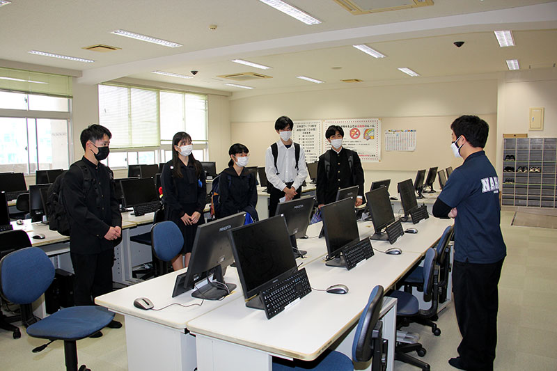 那覇高校の情報室で垣花康夫先生から機器の操作方法について指導を受ける